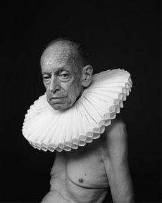 an old man with a paper collar around his neck and shoulders, posing for a black and white photo