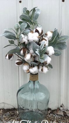 a glass vase with cotton and eucalyptus in it