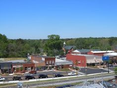 an aerial view of a train station with cars parked on the tracks and trees in the background