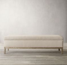 a white bench sitting on top of a hard wood floor next to a gray wall