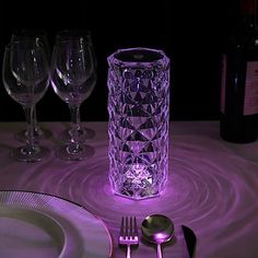 the table is set with wine glasses, silverware, and an illuminated candle holder