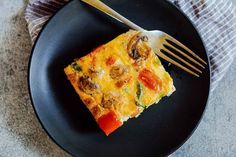 a piece of quiche on a black plate with a fork