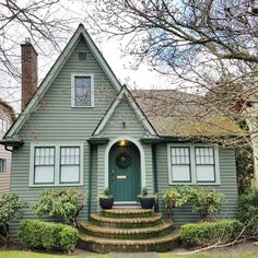 a green house with steps leading up to the front door