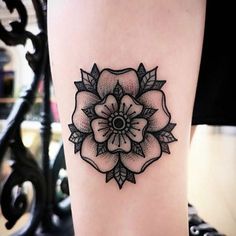 a black and white flower tattoo on the right side of the leg, with an arrow in the center