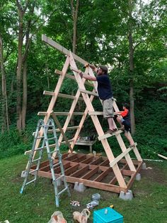 two men working on a wooden structure in the woods