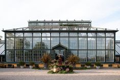 a large glass building with lots of windows and plants in the front yard on a sunny day