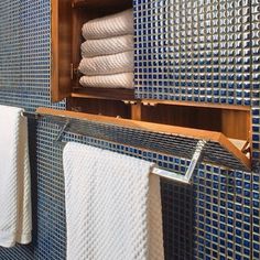 a bathroom with blue tile and white towels hanging on the rack in front of it