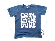 "Retro Boys Shirt/Retro Toddler Shirt/Retro Baby Shirt/Cool Little Dude Shirt/Smiley Face Shirt/Baby Shirt/Toddler Shirt/Gender Reveal/Gift 'COOL LITTLE DUDE' TEE - a cute, comfy, retro style for your little dude! Indigo blue tee with white vinyl font. See all the adorable tees H+A has to offer! heartandarrowbtq.etsy.com Follow along on Instagram @shopheartandarrow PLEASE NOTE: SHIPPING SPEED DOES NOT AFFECT PROCESSING TIME. IF YOU NEED YOUR ITEM BY A CERTAIN DATE, PLEASE MESSAGE ME BEFORE ORDER Little Boy Shirts, Cute Blue Shirt With Funny Print, Baby Boy Shirt Design, Kids Tees, Casual Tops With Funny Text For Playtime, Funny Blue Tops For Playtime, Fun Funny Print Shirt, Baby Boy Cricut Shirts, Trendy Graphic Print T-shirt For Playtime