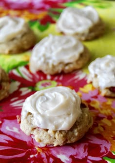 cookies with white icing on a red and yellow table cloth next to some flowers