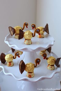 three tiered white cake plate with gold decorated turkeys on top and chocolate candies in the middle