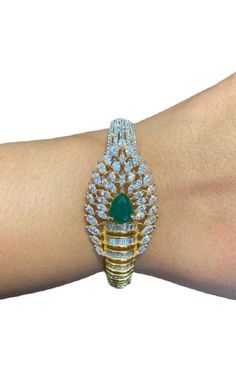 "Discover an exquisite gold-plated bracelet featuring intricate designs and stunning emerald green stones. This openable diamond bracelet, also known as a Pakistani kada or bangle, combines the elegance of CZ with traditional craftsmanship. Perfect for adding a touch of luxury to any outfit." Our products are meticulously handcrafted, ensuring each piece is unique. Due to the manual craftsmanship, you may notice slight irregularities, which are natural and do not compromise the quality of the jewelry. Gold Bangle Bracelet With American Diamonds, Gold American Diamond Bangle Bracelet, Festive Cubic Zirconia Bangle Bracelets, Gold Cubic Zirconia Bracelet For Festive Occasions, Festive Gold Bracelets With Cubic Zirconia, American Diamond Bangle Bracelets As Gift, Festive Gold Bracelet With Cubic Zirconia, Diamond Kada Bracelets, Modern Diamond Jewelry