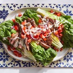 lettuce and tomato salad on a plate with blue flowered tablecloths