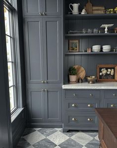 a kitchen with gray cabinets and checkered flooring on the floor, along with white counter tops