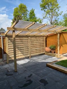 a backyard with a wooden pergolan and green grass on the ground next to it