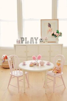 a white table with pink chairs and two teddy bears