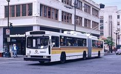 a city bus driving down the street in front of a tall building with many windows