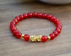 "This is Pure Real 24 Karat Gold Pixiu/Natural Carnelian Gold Pixiu Piyao( less than 1 g ) - Approximately 13mm x 6mm 14 karat Gold Beads Round - Approximately 3mm Carnelian Beads - Approximately 6mm Hallmark/Stamp 999 for 24k Gold (PIXIU) Please select bracelet size. All are handmade with care .Strung on heavy duty stretchy/elastic. Products and photo may differ. Bracelet Comes with Storage Bag & Box How to Determine Bracelet Size: Step 1: Measure your wrist just below the wrist bone, where Red Carnelian Bracelets With 8mm Beads, Gold Carnelian Beaded Bracelets For Spiritual Wear, Hand-strung Carnelian Bracelets Gift, Hand-strung Carnelian Bracelet As Gift, Red Carnelian Beaded Bracelets For Gift, Spiritual Red Agate Bracelets, Red Carnelian Bracelets As Gift, Red Carnelian Bracelets As A Gift, Red Agate Bracelets For Meditation