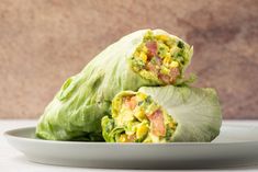 two pieces of lettuce wrapped in bacon and cheese on a plate with a marble background