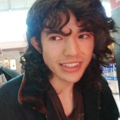 a young man with long hair is smiling at the camera