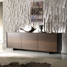 a large wooden cabinet sitting in front of a wall covered with white paper strips and vases