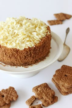 there is a cake with white frosting and cookies on the plate next to it