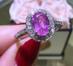 a close up of a person holding a ring with a large pink stone in it