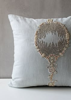 a decorative pillow with beading on the front and back of it, sitting on a white table