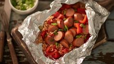 there are some sausages and rice in the foil wrapper on the table with chopsticks next to it