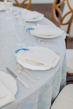 the table is set with white plates and silverware