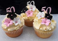 four cupcakes with white frosting and pink flowers on them are arranged in the shape of 50