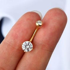 a person holding a gold nose ring with a diamond in it's middle,