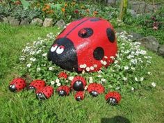 a red ladybug statue sitting on top of a lush green field