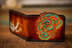 a leather wallet with an embroidered rose on it