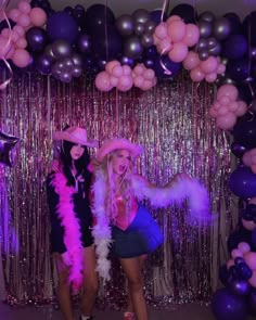 two women standing next to each other in front of balloons