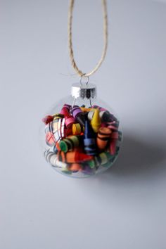 a glass ornament filled with colorful candy on a white table next to a string