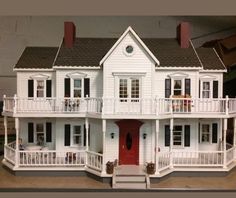 a white doll house with balconies and red door