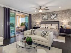 a bedroom with a large bed, couch and chair next to a sliding glass door