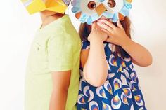 two young children with paper masks on their faces, one holding the other's face