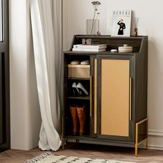 a wooden cabinet sitting next to a window with white curtains and shoes on top of it