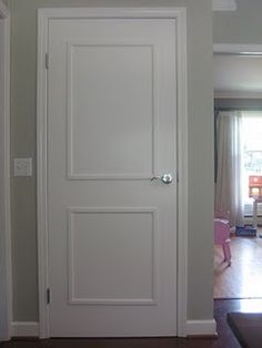 an open door leading to a living room with hard wood flooring and white walls