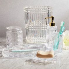 bathroom accessories including soap dispenser, toothbrush holder and glass container on marble countertop