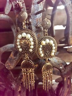 Exquisite one-of-a-kind drop earring. Done in antique gold finishing with beautiful carvings. The delicate pearls are beautiful, and pairs well with the show stopping metal fringe.

The Leah earring will pair amazing with any Dreamers & Lovers dress. It is the perfect earring option for the bohemian bride.

- Clip on style Elegant Tassel Teardrop Earrings, Elegant Teardrop Tassel Earrings, Elegant Antique Finish Earrings For Festive Occasions, Elegant Tassel Earrings In Brass, Bohemian Dangle Pearl Earrings For Party, Bohemian Pearl Drop Earrings For Party, Bohemian Pearl Earrings With Dangling Beads, Bohemian Pearl Drop Earrings, Bohemian Pearl Earrings With Latkans For Weddings