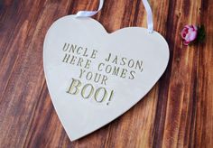 a heart shaped plaque with the words uncle mason here comes your boo on it next to a flower