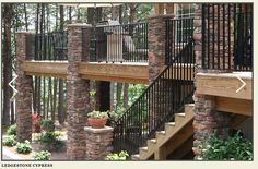 an outdoor stair case with stone pillars and wrought iron railings, along with potted plants