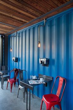 two red chairs sitting next to each other in front of a blue wall with striped walls