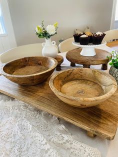 three wooden bowls sitting on top of a table next to vases with flowers in them