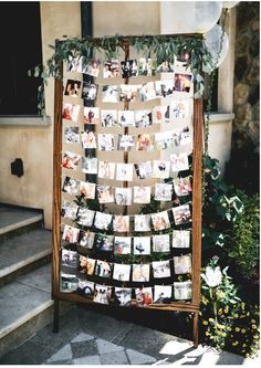 a wooden frame with pictures hanging on it and some flowers in front of a building