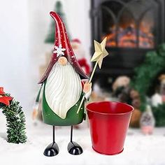 a christmas scene with a gnome holding a star next to a red cup and potted plant