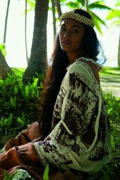 a woman sitting on the ground in front of palm trees wearing a headband and dress