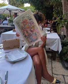 a woman sitting at a table reading a book